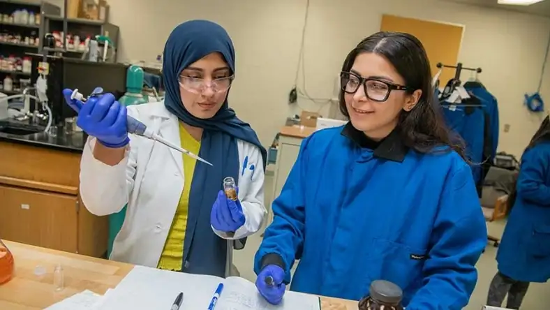 Researchers wearing safety gear conduct laboratory tests with pipettes and sample vials
